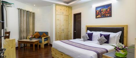 Een hotelkamer met een bed, een bureau, een stoel, een kledingkast en een schilderij aan de muur.