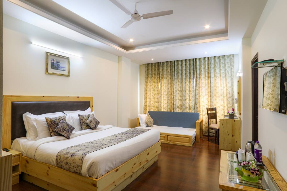 A hotel room with a large bed, a smaller bed, a desk, and a chair.