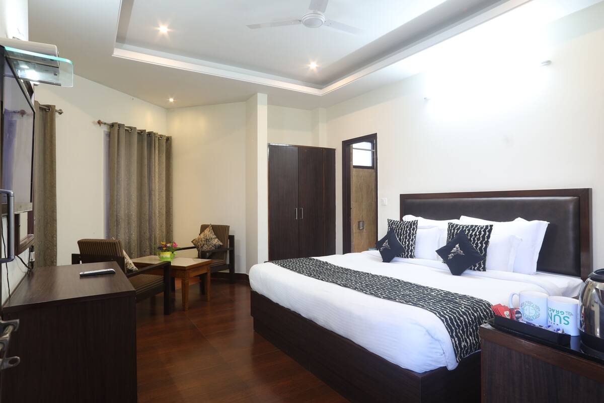 A hotel room with a bed, a desk, a chair, a table, and a wardrobe.