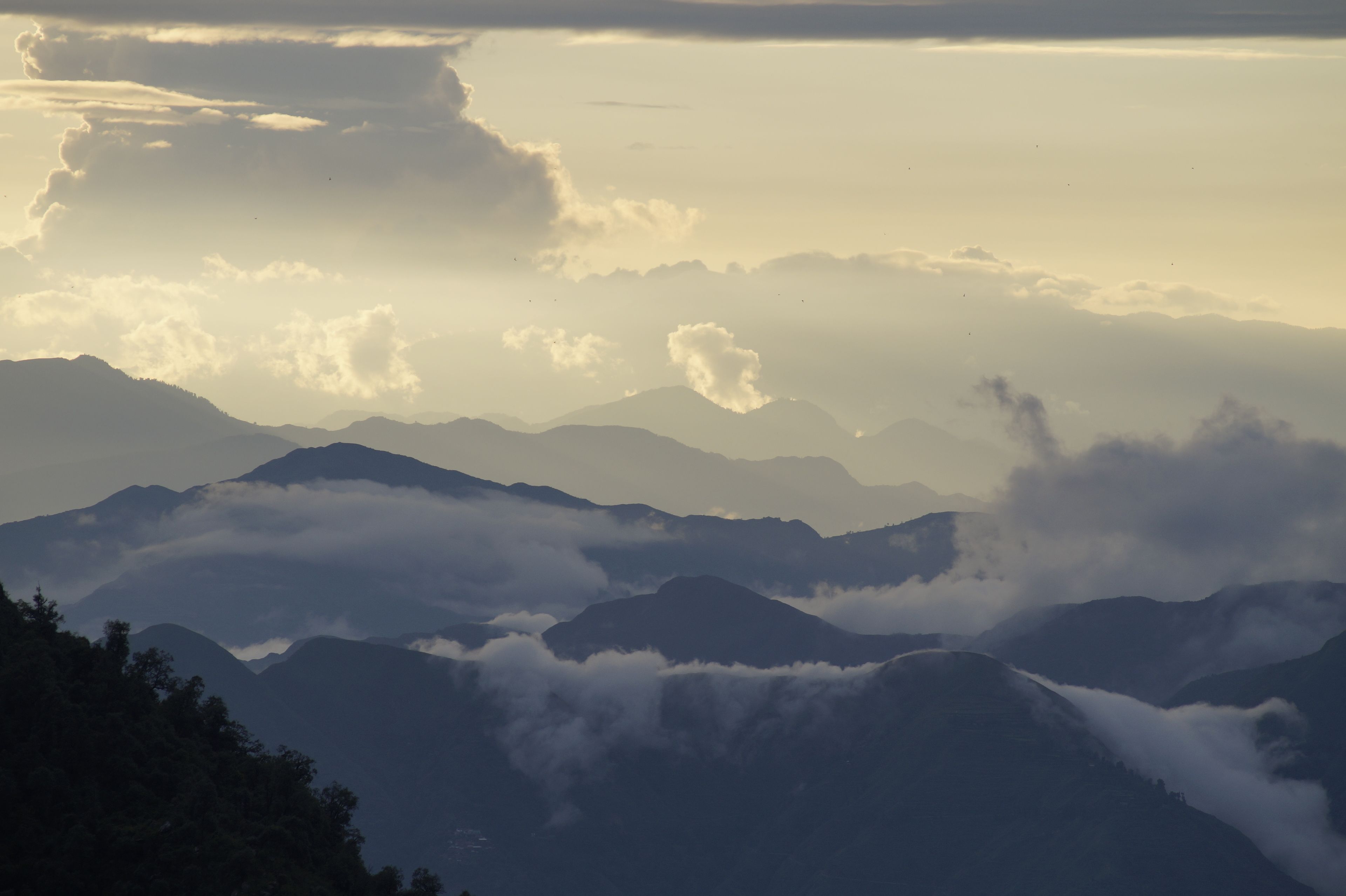 A mountainous landscape with layers of clouds and mist.