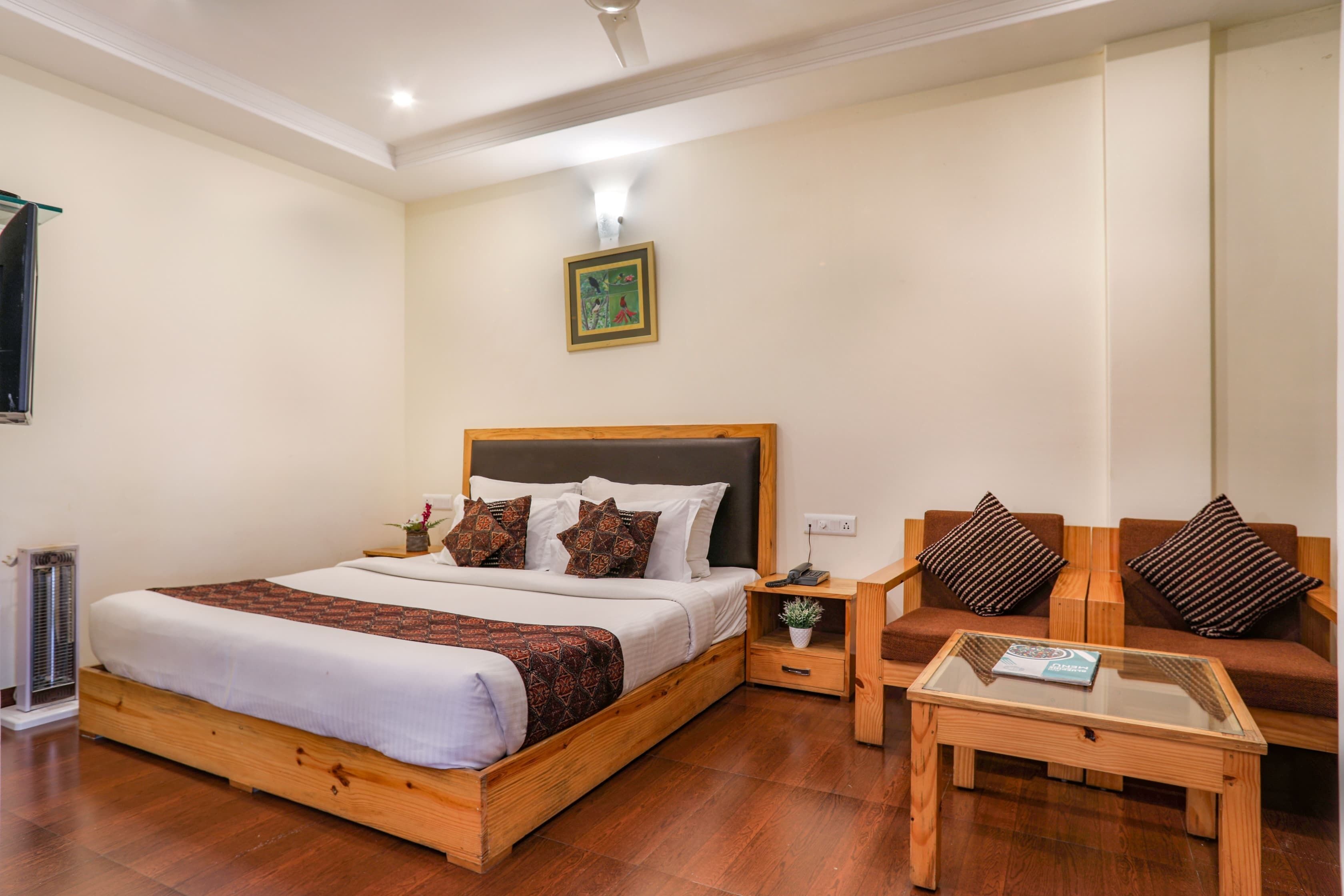 A bedroom with a wooden bed, a nightstand, a glass coffee table, and a brown sofa.