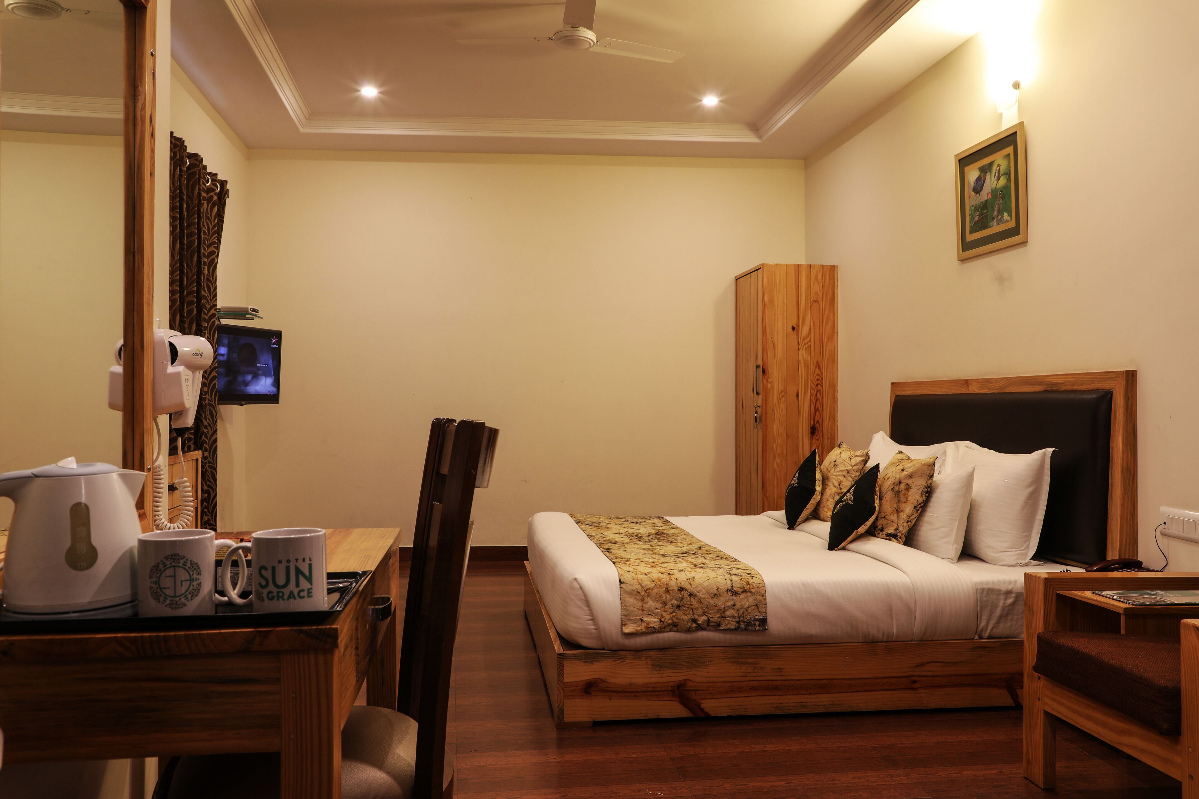 Una habitación de hotel con una cama, un escritorio con hervidor, dos tazas, una silla y un televisor.