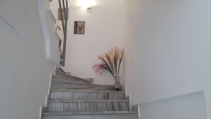 A staircase with a vase of dried plants at the bottom. - Orange Fodele (Malevizi)