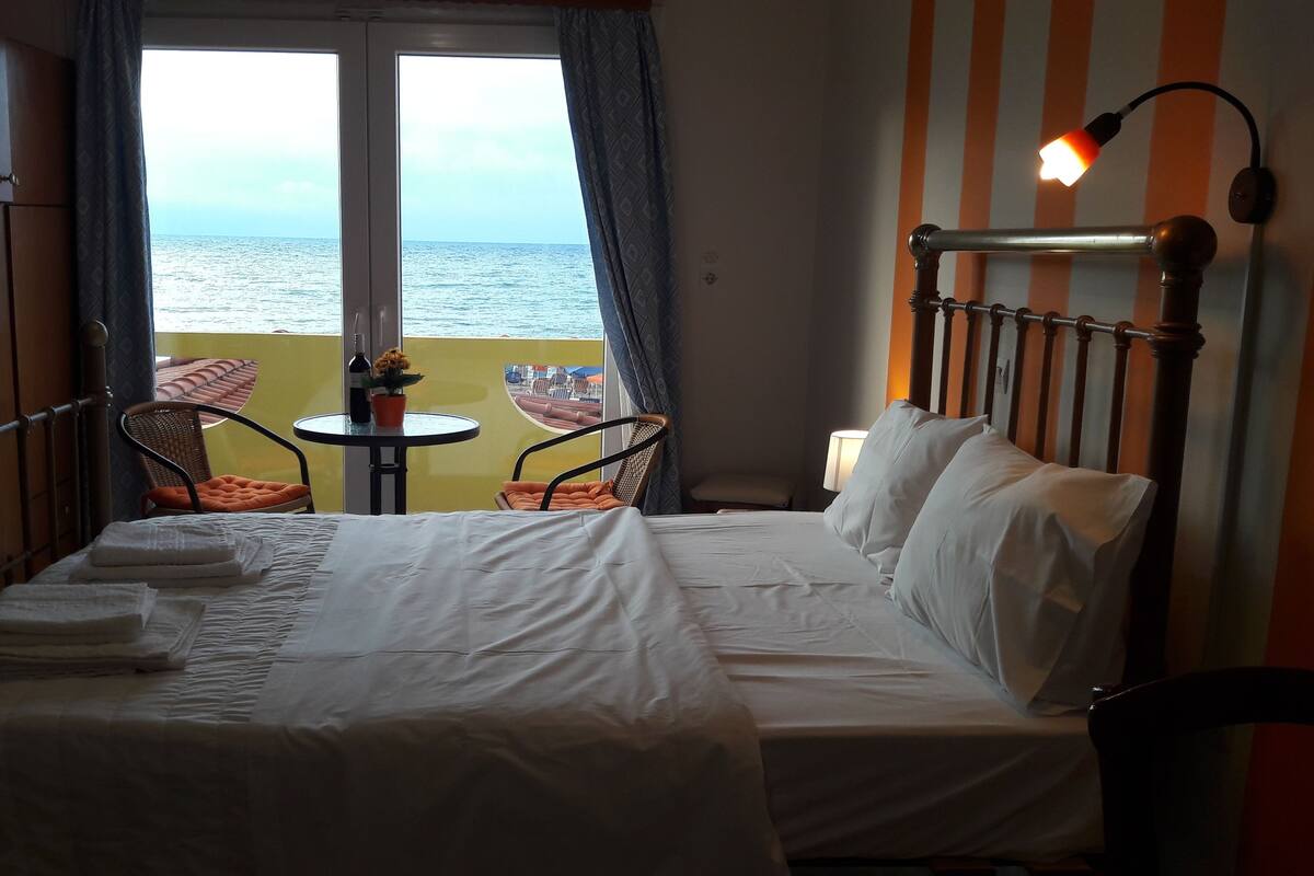 Une chambre d’hôtel avec un lit, deux chaises, une table et une vue sur la mer.