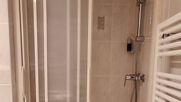 A modern bathroom with a glass-enclosed shower, a white toilet, and a white towel hanging on the wall.