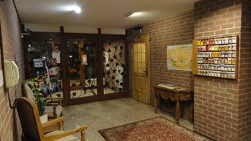 A lobby with a wooden chair, a red patterned rug, a map on the wall, and a door leading to another room.