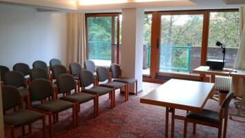 A conference room with rows of chairs, a table, and large windows with a view of trees.