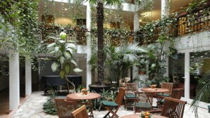 A multi-level atrium with indoor plants, wooden furniture, and a stone floor. - Solitaire Hotel & Boardinghouse Berlin (Berlin)