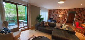 A living room with a sofa, armchair, and a dining area with a table and chairs.