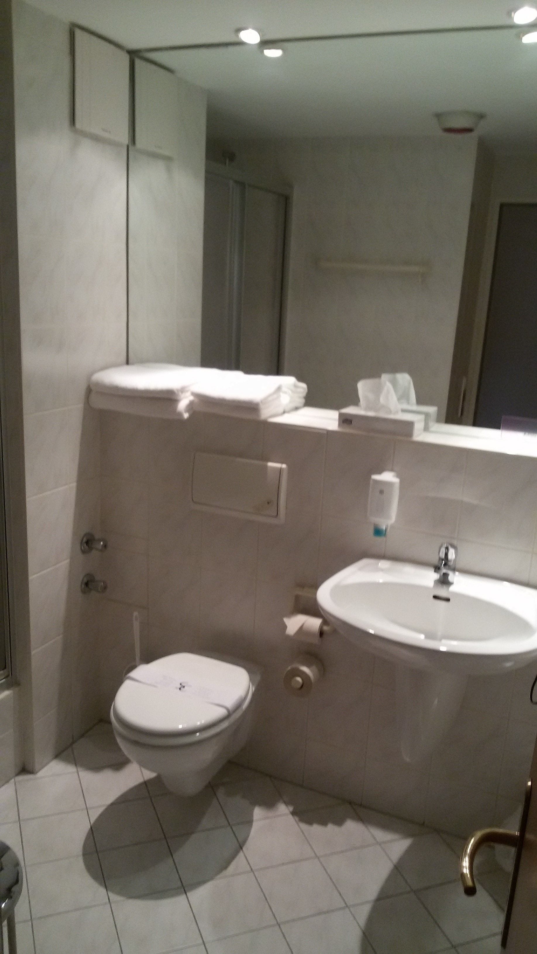 A modern bathroom with a toilet, sink, and towel rack.