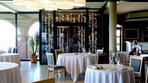 A restaurant interior with round tables, chairs, and a wine rack in the background. - Tota Virginia Antico Podere (Serralunga d'Alba)