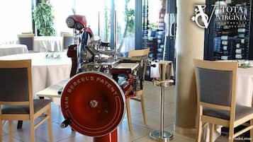 Ein Essbereich mit einem Vintage-Mechanikgerät, einem Tisch mit weißer Tischdecke und Stühlen mit grauen Kissen.