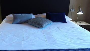 A neatly made bed with white bedding and two pillows, flanked by two bedside lamps on matching nightstands.