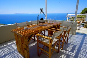A wooden table with chairs on a balcony overlooking the sea. - Villa Alisachni (Andros)