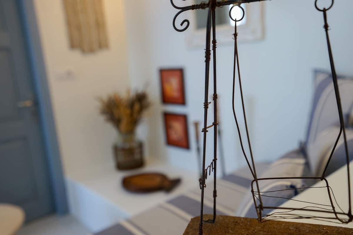 A bed with a metal frame, a vase with dried plants, and a framed picture on the wall.