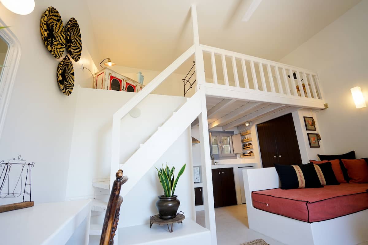 A modern interior with a white staircase, a red sofa, and a kitchen area.