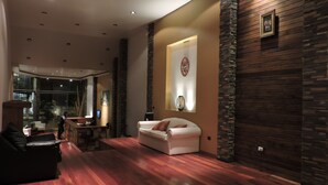 Ein modernes Wohnzimmer mit einem weißen Sofa, Holzboden und einer Wand als Akzent aus Stein.