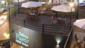 Eine Dachterrasse mit Tischen, Stühlen, Sonnenschirmen und einem Schild für das „Patio del Puerto Hotel Boutique“.