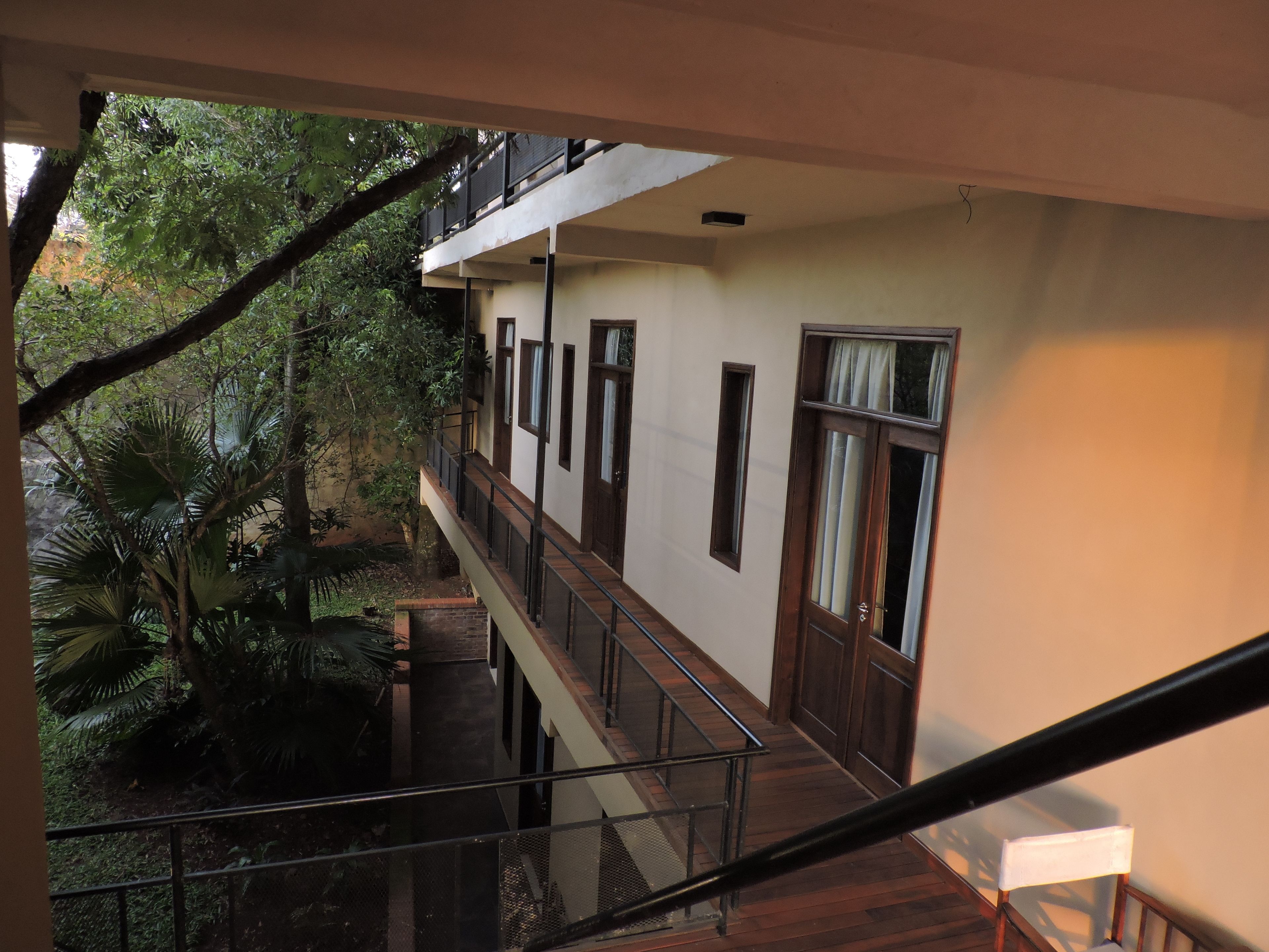 A multi-level building with balconies, a staircase, and surrounding greenery.
