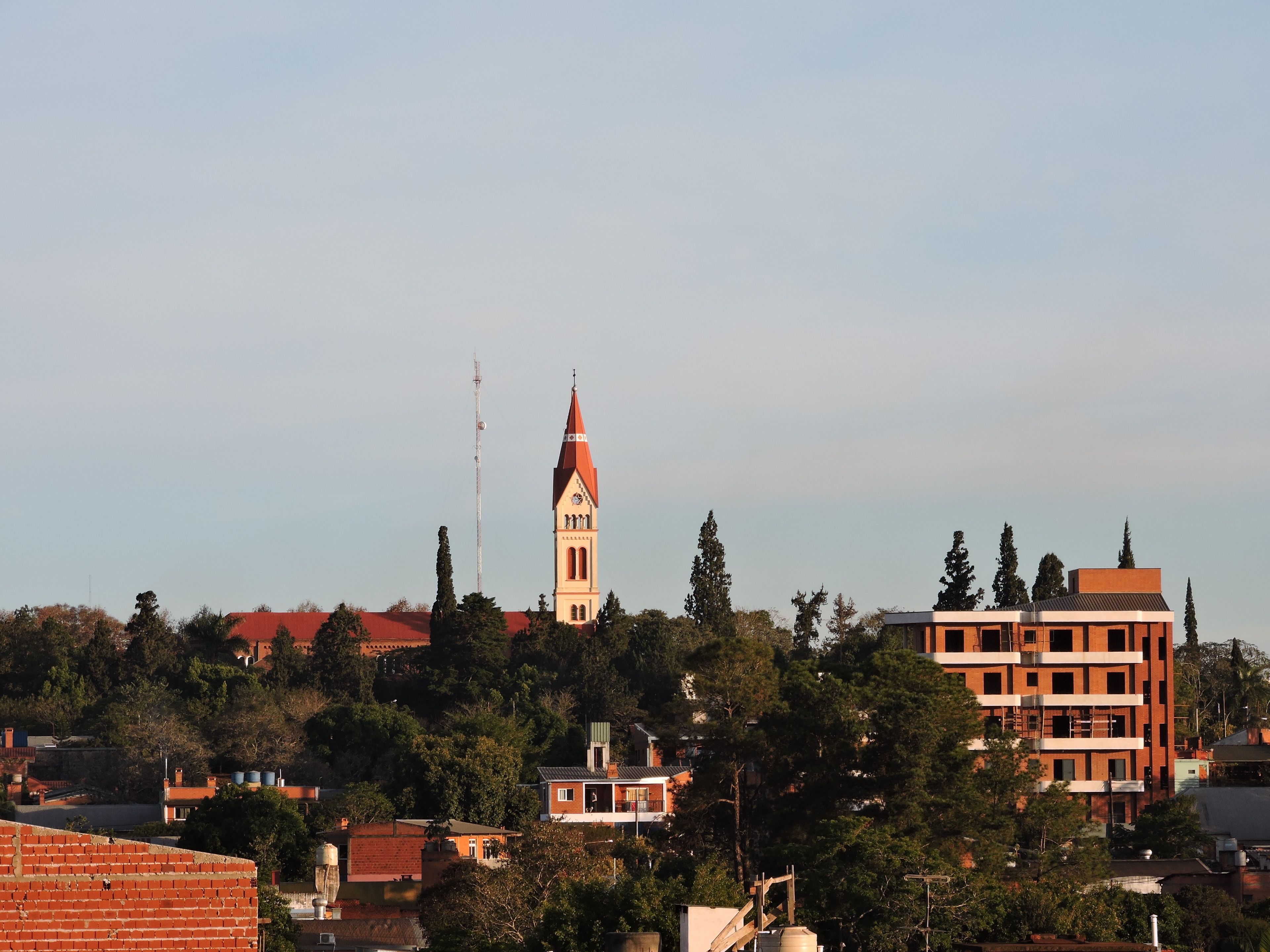 A church with a tall steeple, surrounded by residential buildings and trees.