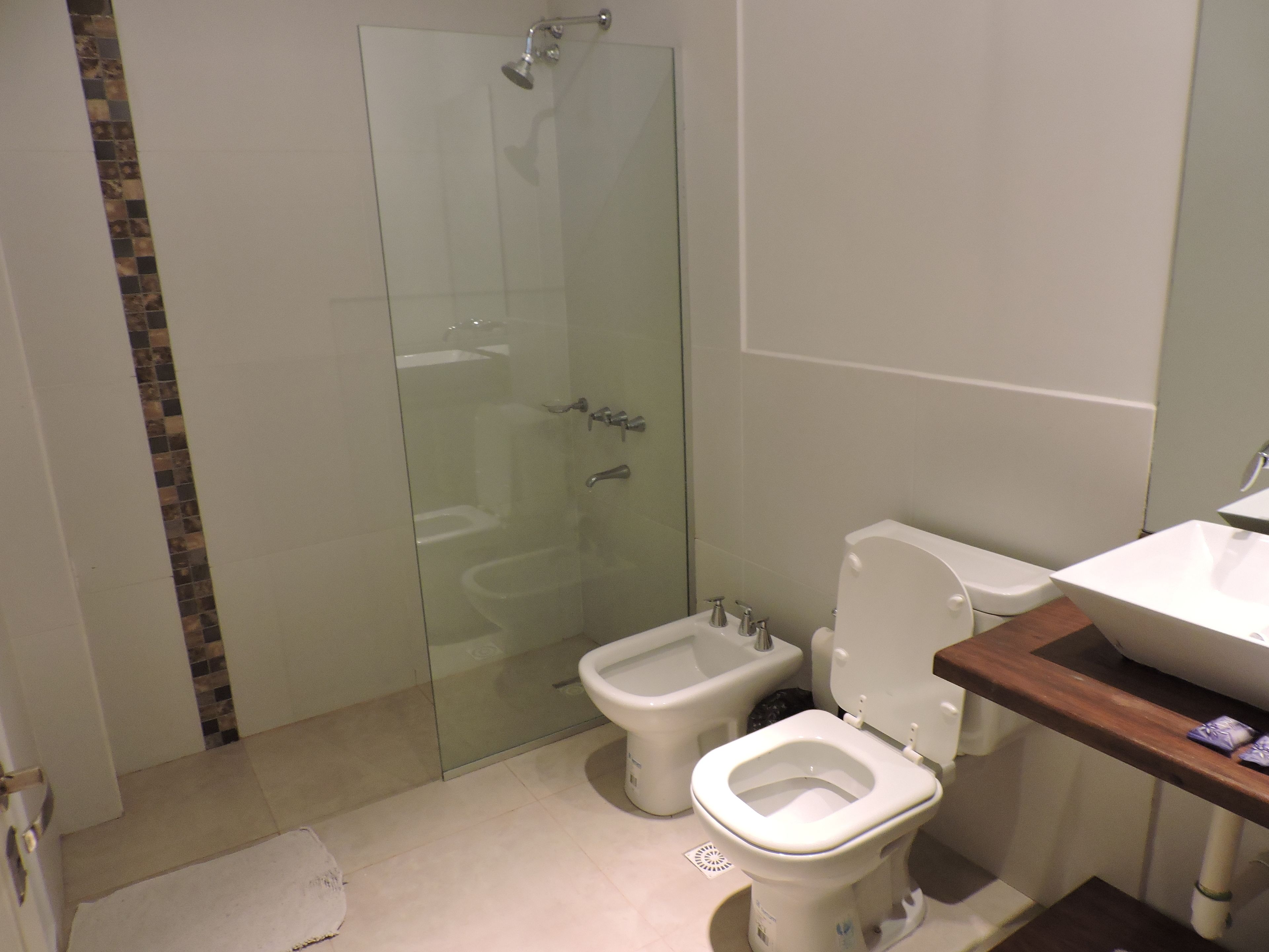 Ein Badezimmer mit Duschkabine, integriertem Bidet, Toilette und Waschbecken.
