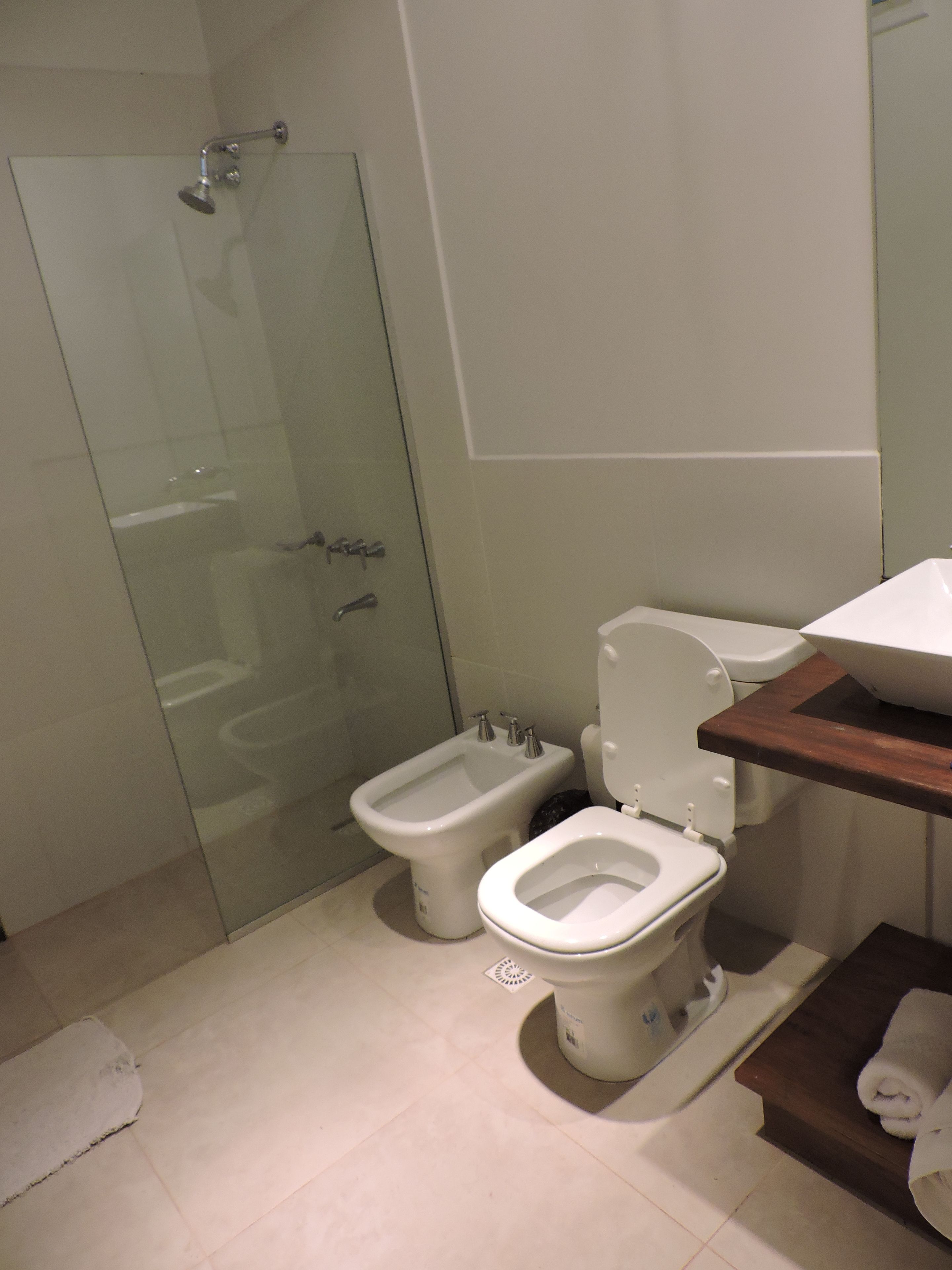 Un baño con ducha envuelta en vidrio, un bidé y un inodoro.