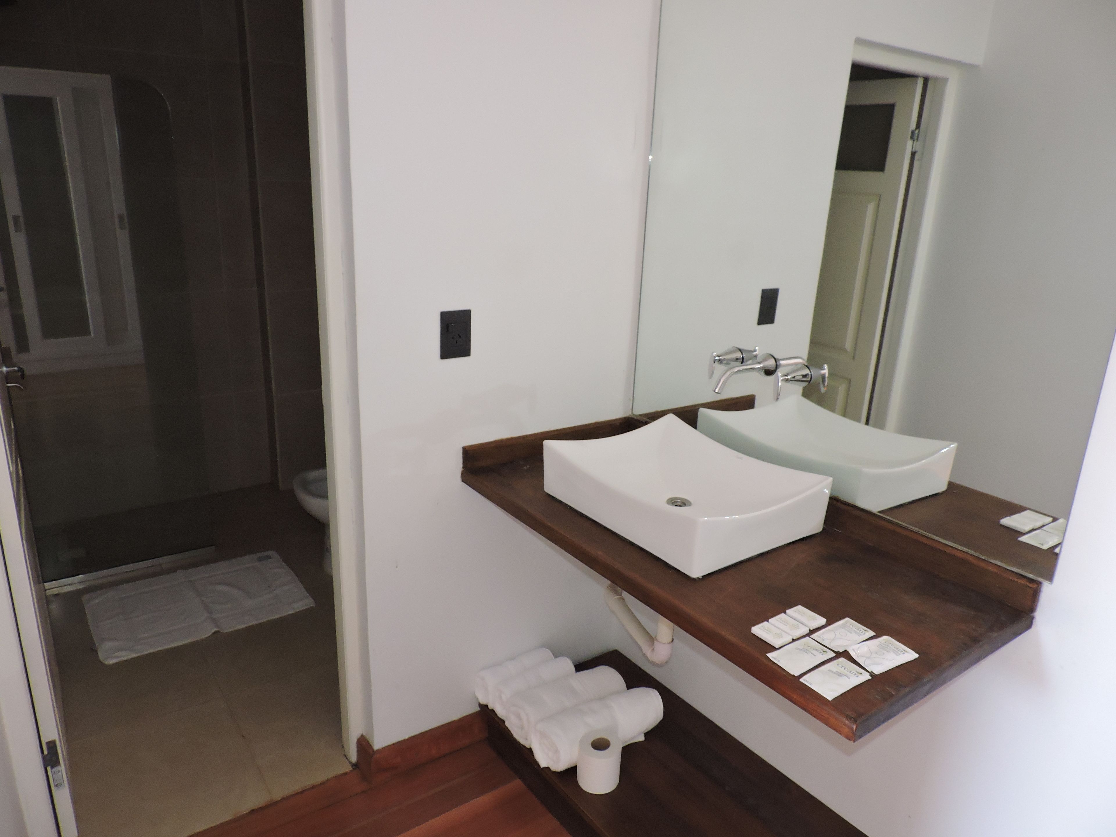 A bathroom with a white sink, a mirror, and a shower area.
