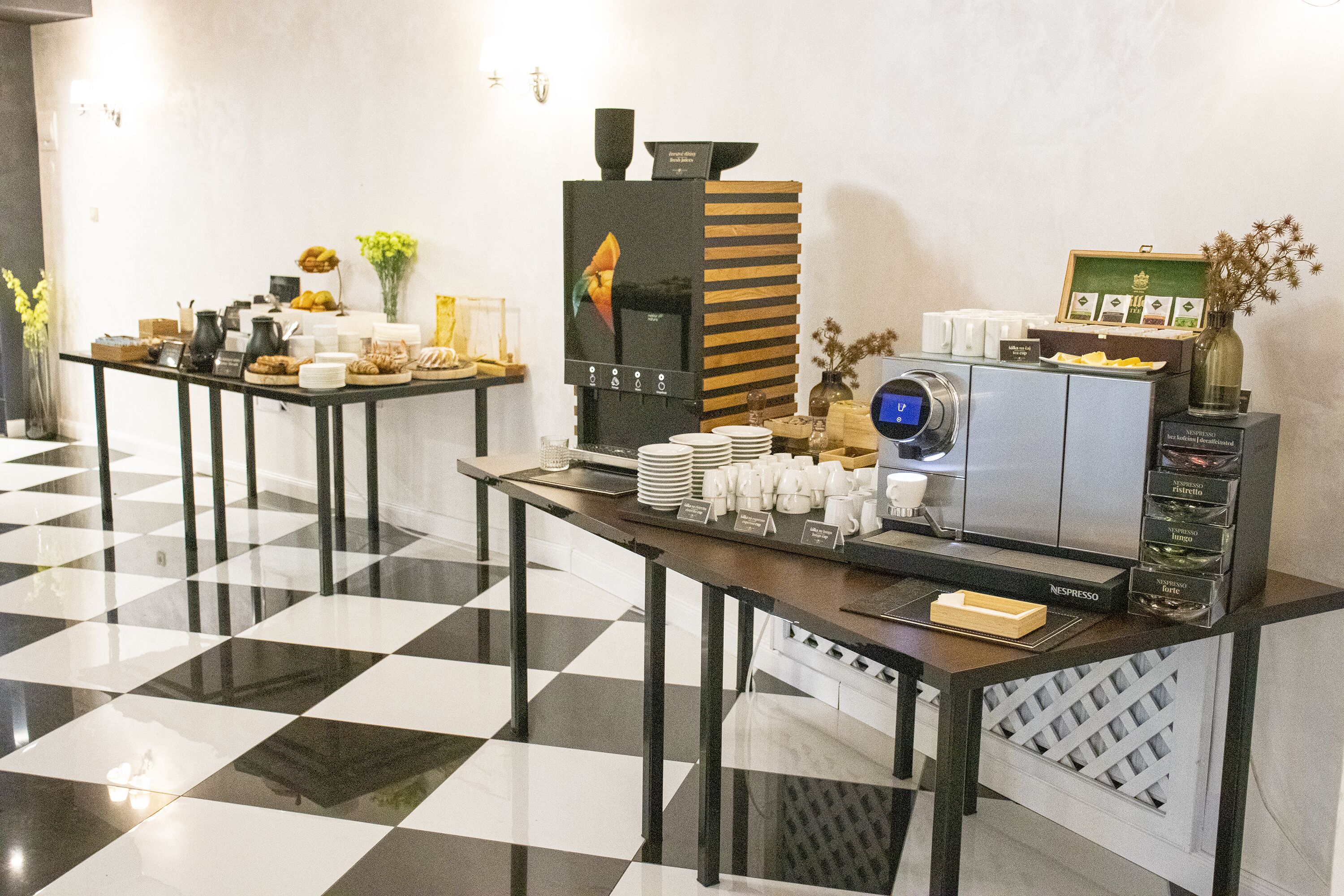 Een ontbijtbuffet met een koffieapparaat, borden, bekers en verschillende soorten eten.