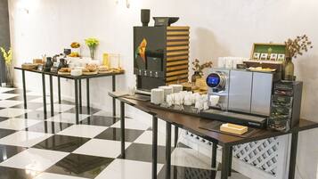 Een ontbijtbuffet met een koffieapparaat, borden, bekers en verschillende soorten eten.