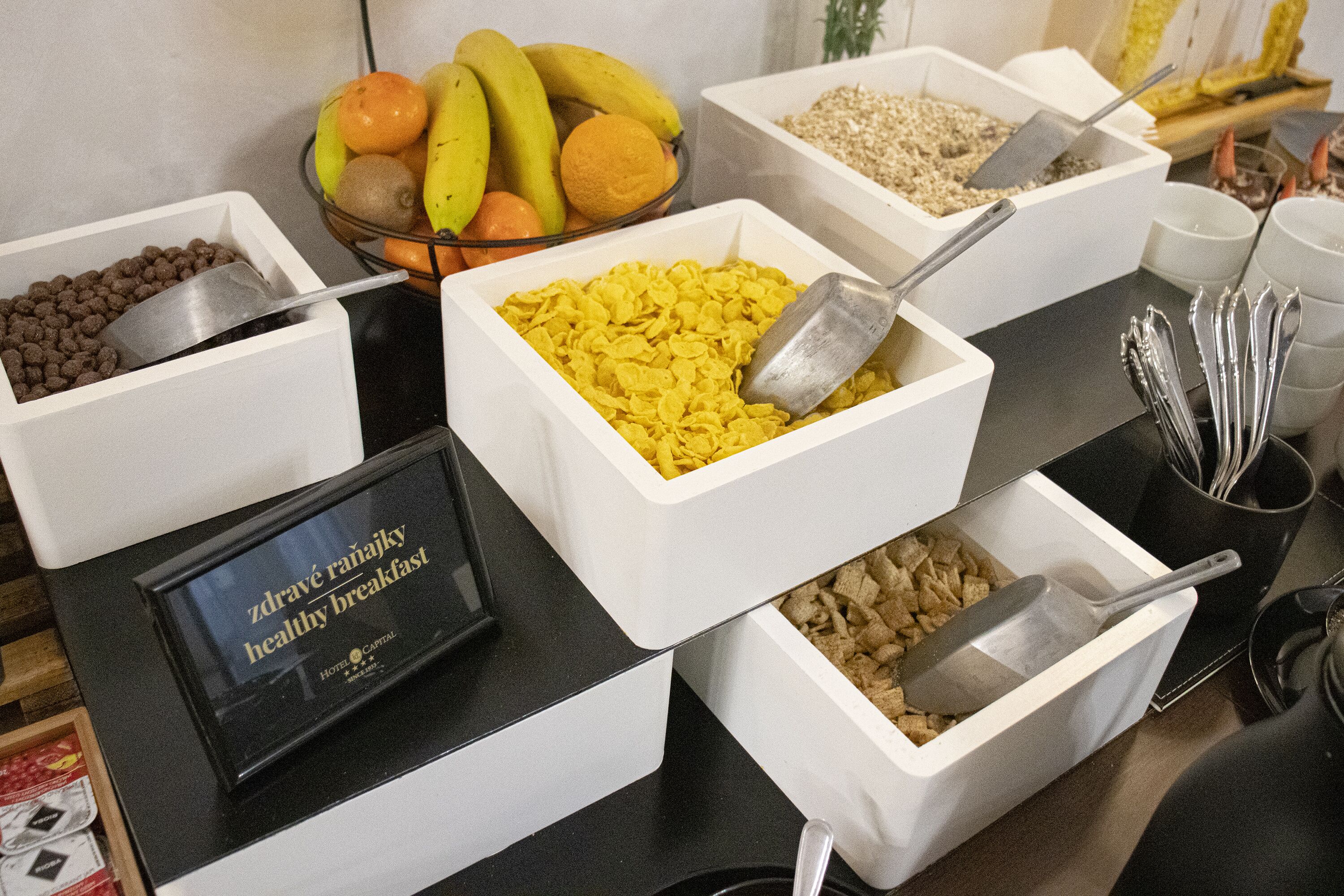 A buffet with various food options including cereal, fruits, and grains.