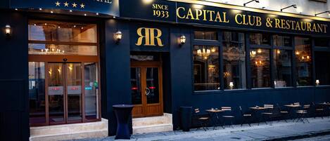 A hotel exterior with a sign reading "Hotel Capital" and "Capital Club & Restaurant" since 1933.