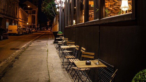 A nighttime street view of a restaurant with outdoor seating, a clock, and a sign reading "Slovak Republic." - Hotel Capital (Nitra)