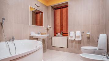 A modern bathroom with a large bathtub, a toilet, a sink, and a shower.