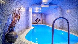 A small, tiled indoor pool with a clear blue water feature, a decorative vase with branches, and a mural of a fish on the wall. - Hotel Capital (Nitra)