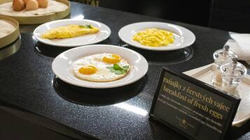 Un buffet della colazione con diversi piatti, tra cui uova strapazzate, omelette e uova fresche.