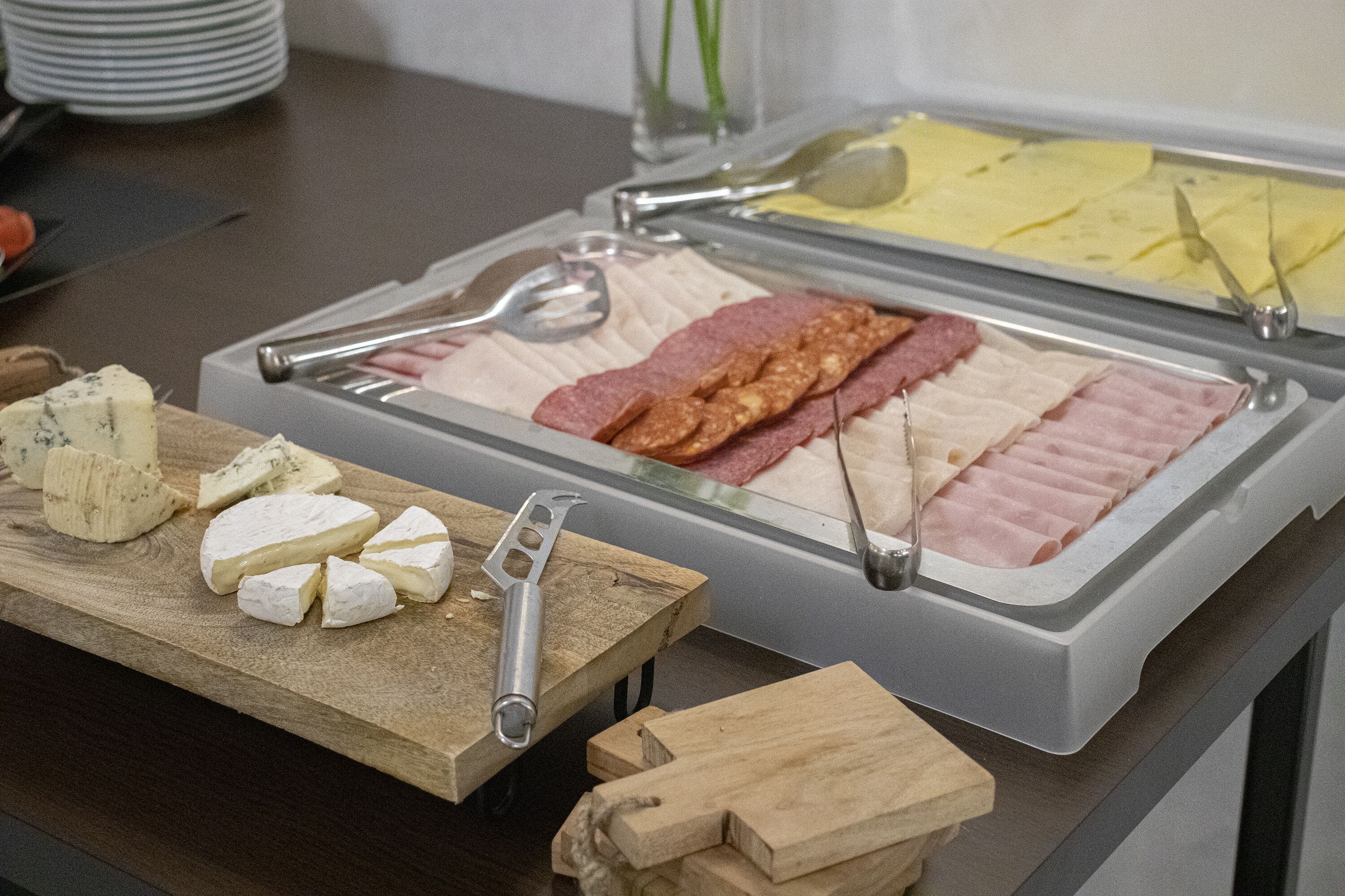A buffet with various cheeses, meats, and fruits.
