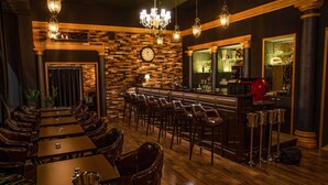 A bar area with wooden flooring, leather chairs, and a brick wall with a clock. - Hotel Capital (Nitra)
