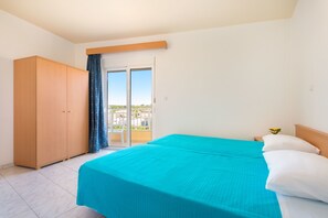 A bedroom with a bed, a wardrobe, a balcony with a view, and a window with curtains. - Yiannis Apartments (Rhodes)