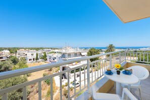 A balcony with a white table, two blue cups, and a yellow flower. - Yiannis Apartments (Rhodes)