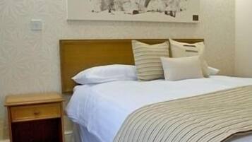 Een hotelkamer met een bed, nachtkastje en een kunstwerk aan de muur.