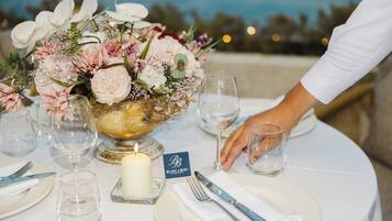 A table set with a candle, a glass bowl with flowers, and a name card.