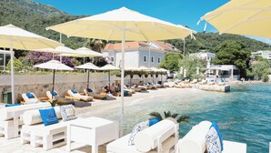 A beachside hotel with white lounge chairs, yellow umbrellas, and a pool. - Boutique Hotel and Spa Blanc & Bleu - Blanche (Bijela)