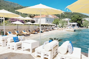 A beachside hotel with white lounge chairs, yellow umbrellas, and a pool. - Boutique Hotel and Spa Blanc & Bleu - Blanche (Bijela)