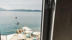 A view of a calm lake with a dock, lounge chairs, and umbrellas. - Boutique Hotel and Spa Blanc & Bleu - Blanche (Bijela)