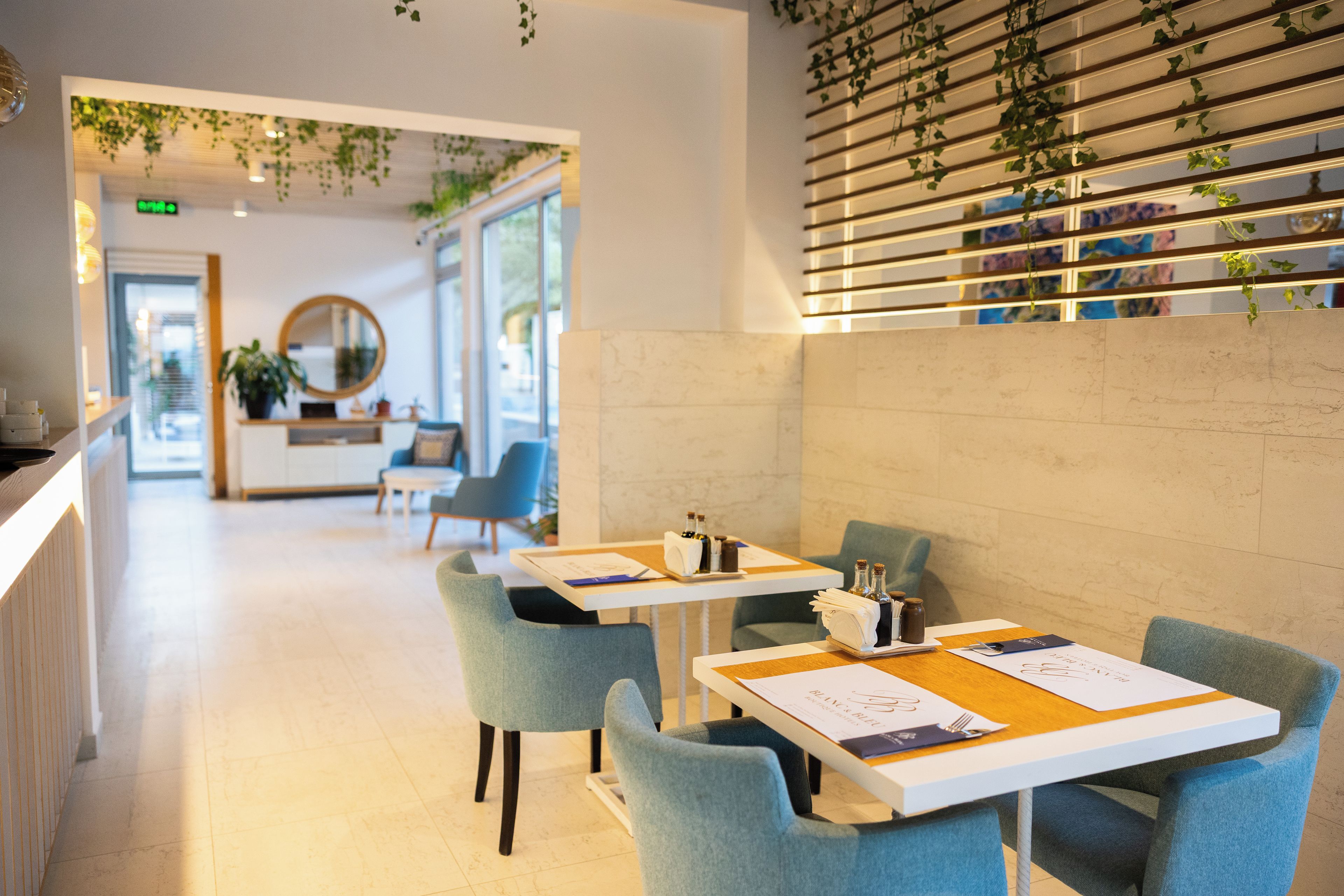 A modern interior with a reception desk, seating area, and a wall with hanging plants.