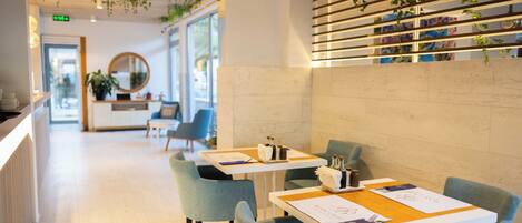 A modern interior with a reception desk, seating area, and a wall with hanging plants.