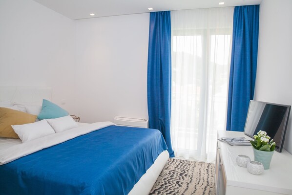 A modern bedroom with a bed, a desk, and a window with blue curtains. - Boutique Hotel and Spa Blanc & Bleu - Blanche (Bijela)