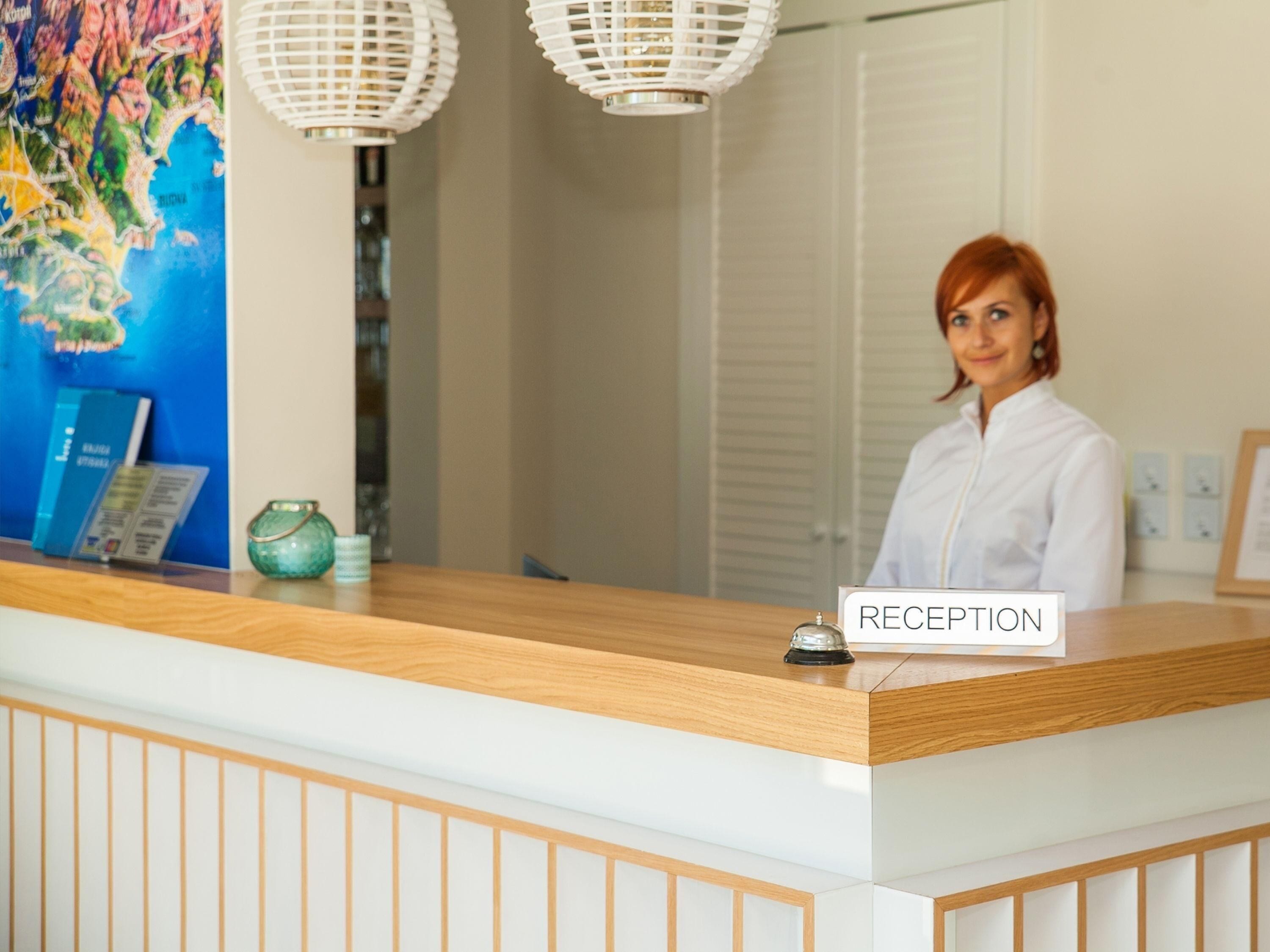 A reception desk with a 'RECEPTION' sign, a map on the wall, and a green vase.