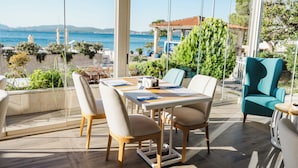 A sunlit outdoor dining area with a table set for two, overlooking a coastal view. - Boutique Hotel and Spa Blanc & Bleu - Blanche (Bijela)