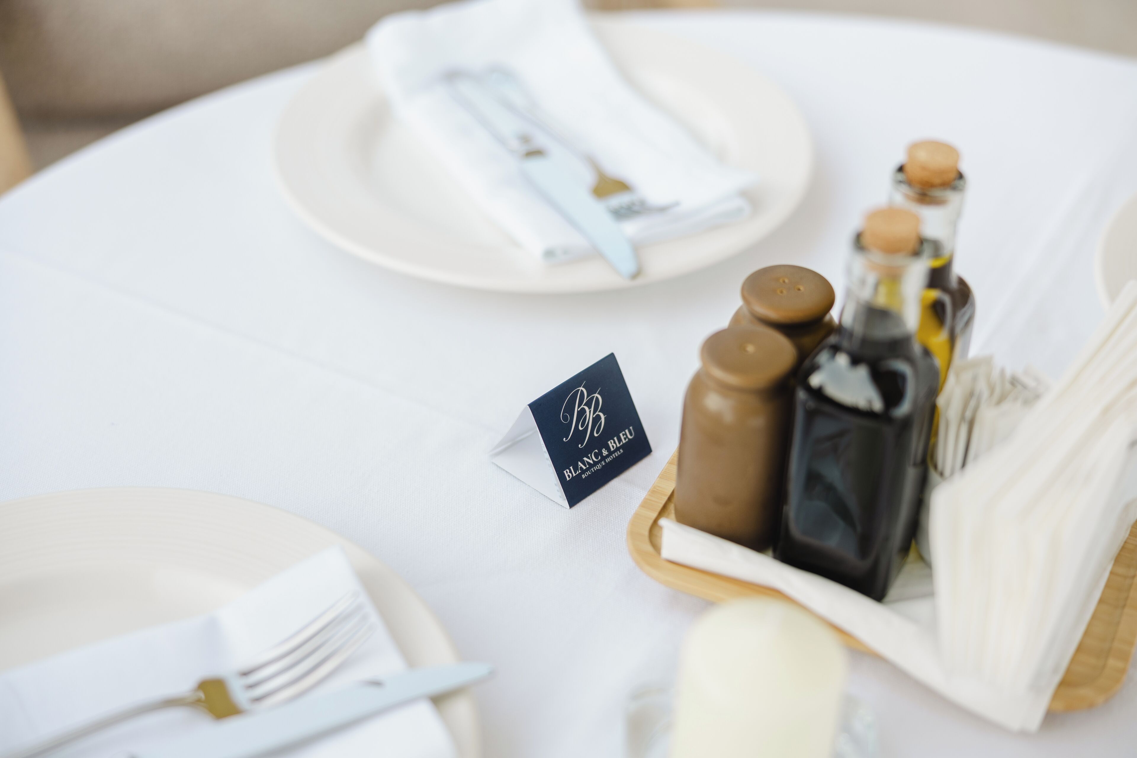 A table set with white plates, cutlery, and a small card with 'BLANC & BLEU' text.
